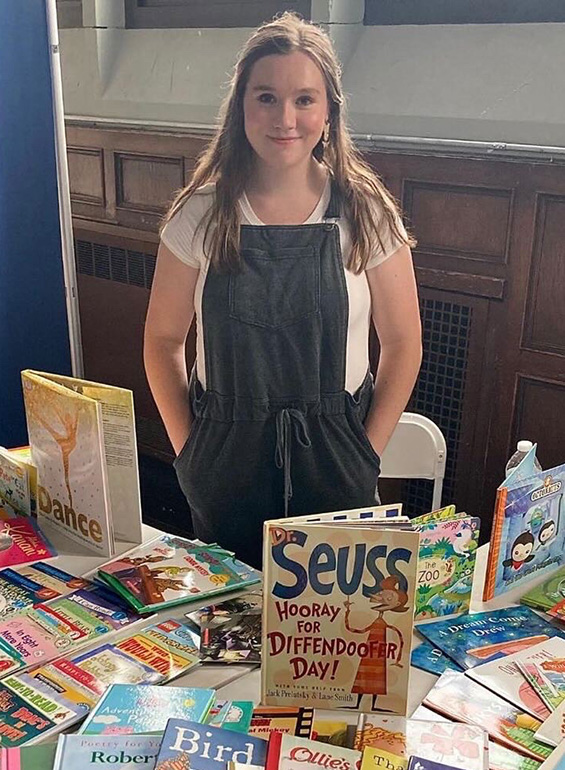 Erin Letourneau poses for a photo behind a table filled with books.
