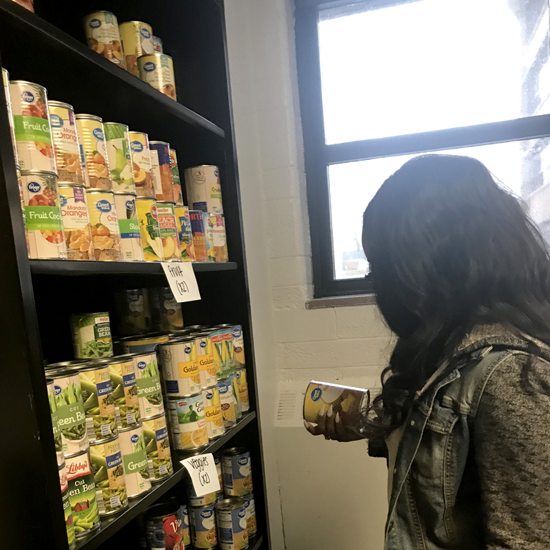 An anonymous ɫۺϾþ Mercy student selects canned goods from the shelf.